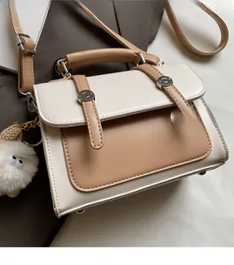 Detail of color-block crossbody bag with plush lamb charm and metallic buckle closure