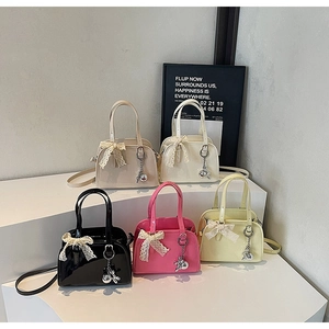 Detail of glossy Boston bags with lace bows and silver rabbit charms in multiple colors