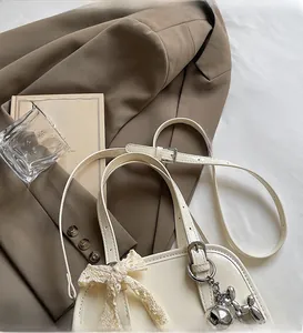 Close-up of beige leather Boston bag featuring lace bow and metallic balloon dog charm