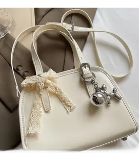 Detail of cream patent leather handbag with lace bow and silver dog charm