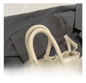 Detail showing the rounded double handles and meticulous stitching of the beige bucket bag