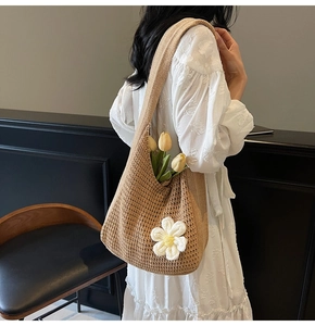Détail d'un sac à bandoulière en maille marron orné d'une grande fleur blanche