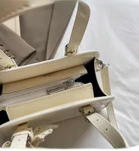 Close-up of smooth metal zipper and glossy cream leather on the large Boston bag