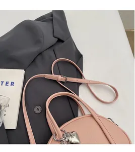 Détail du sac à main rose en cuir litchi avec pendentif coeur et bandoulière réglable