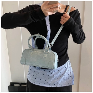 Sac bowling bleu clair brillant porté à l'épaule avec un style de mode minimaliste