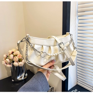Détail du sac blanc à motif crocodile avec chaîne perle et cœur et bandoulière réglable