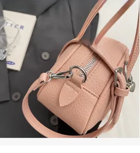 Détail de sac en cuir grainé avec pendentif en cœur argenté et fermeture éclair