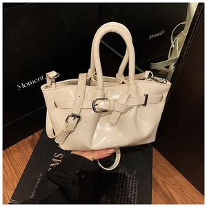 Detail of cream glossy leather bucket bag with silver buckles and handle texture