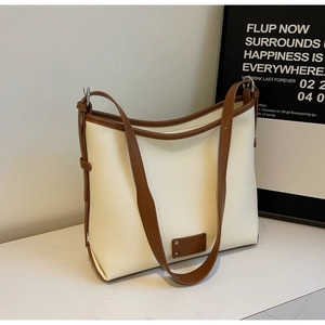 Detailed view of cream and brown pebbled leather tote bag with silver hardware accents