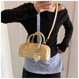 Détail du sac bowling en cuir texturé beige avec breloque cœur perlé et bandoulière