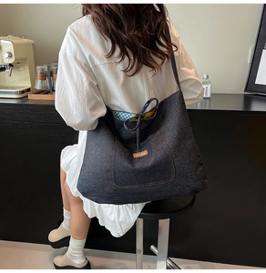 Close-up of large denim tote bag featuring a leather logo patch and colorful lining