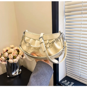 Détail du sac plissé crème avec motif crocodile et chaîne perle et cœur
