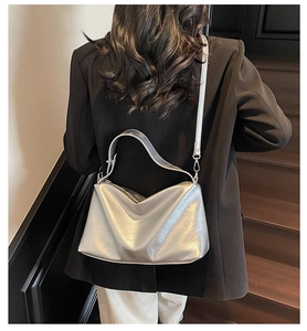 Silver metallic crossbody bag with pleated texture worn by model on stairs