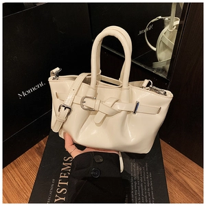 Detail of cream white bucket bag with decorative buckle and smooth leather finish