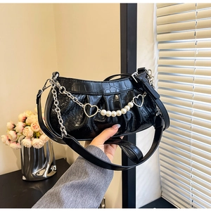Détail du sac noir motif crocodile avec pendentif coeur et chaîne en perles blanches