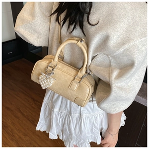 Détail du sac polochon beige avec pendentif coeur en perles et bandoulière