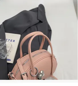 Vue de dessus d'un sac à main rose en cuir grainé avec pendentif en forme de cœur argenté