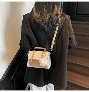 Rear view of a model wearing the cream and brown contrast flap crossbody bag with plush charm