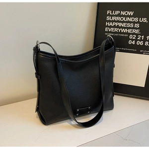 Close-up of black lychee texture leather tote bag with silver metal ring and rivets
