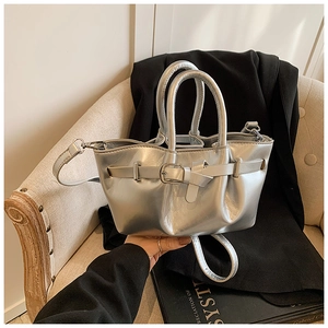 Macro detail of silver metallic bucket bag with belt buckle straps and dual top handles