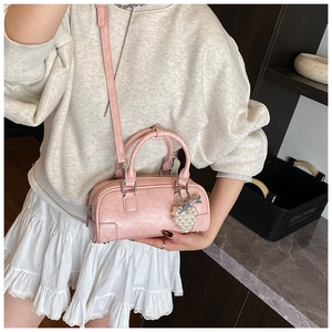 Vue détaillée du mini sac Boston rose avec breloque perle porté par le mannequin