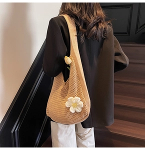 Détail du sac cabas en crochet beige avec fleur tricotée porté à l'épaule par un mannequin
