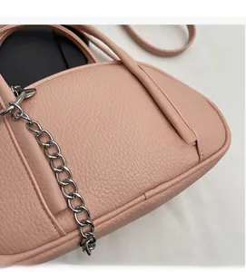 Détail de la texture cuir rose avec chaîne argentée et poignées souples du sac