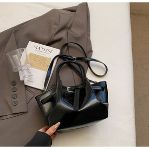 Détails d'un sac seau en cuir verni noir avec boucle métallique et poignées élégantes