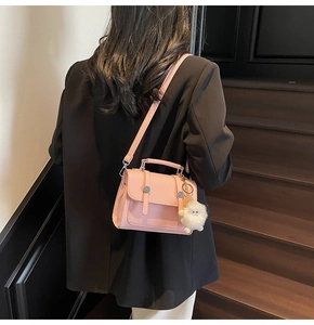 Detailed view of a pink leather crossbody bag with a cute white sheep charm