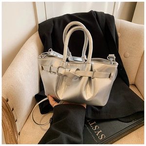 Detailed view of silver metallic bucket bag with decorative buckle and dual top handles