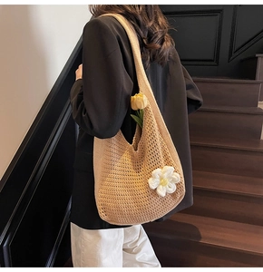 Détail d'un sac cabas en crochet beige avec fleurs 3D tricotées sur escalier en bois