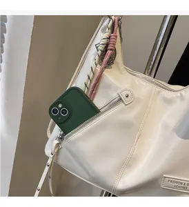 Detail of creamy tote bag showing exterior zipper pocket and braided cord decoration