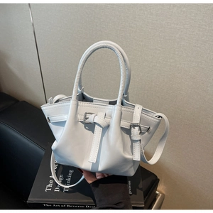Détail d'un sac à main bleu clair en cuir avec boucles métal et doubles poignées