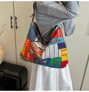 Detailed view of large ethnic patchwork denim tote bag with SEEYOU label on model shoulder
