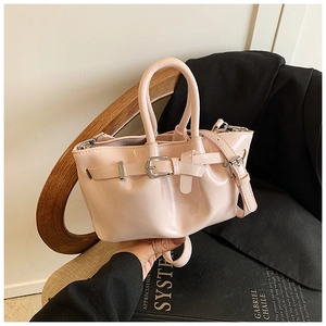Detail of light pink glossy patent leather bucket bag with silver buckles and shoulder strap