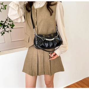Détail du sac croissant noir croco avec chaîne perle et cœur sur tenue beige chic