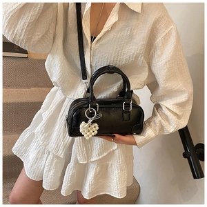 Close-up of black bowling bag with silver hardware and a heart pearl pendant