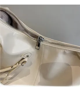 Close-up of smooth silver zipper and precision stitching on off-white leather tote bag