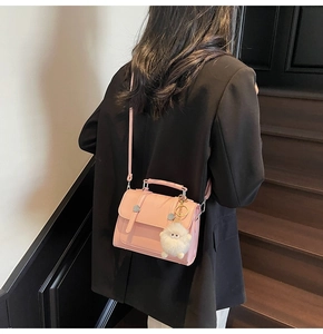 Detailed back view of model wearing pink crossbody bag with a white fluffy keychain charm
