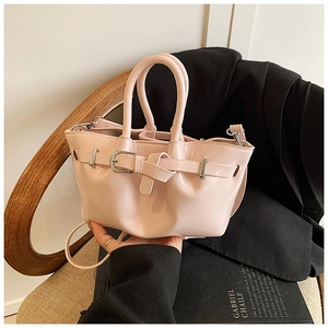Detailed shot of a pink patent leather bucket bag with silver buckle and crossbody strap