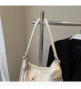 Detail of cream glossy leather hobo bag featuring detachable mini pouch and woven charm