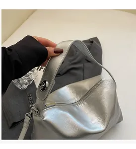 Detail of silver metallic textured pillow bag with comfortable handle and metal lock