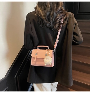 Detailed back view of a pink leather handbag with a plush white monster charm accessory