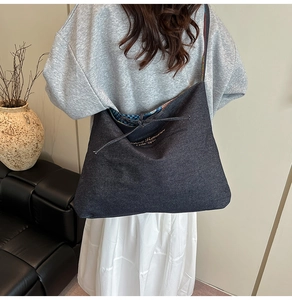 Detail of grey denim tote bag featuring golden Fantasy Romance text and colorful strap weave