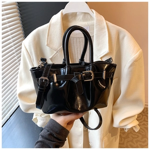Detail of glossy black patent leather bucket bag with silver metal buckle and top handle