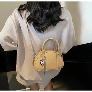 Détail du sac bandoulière avec pendentif cœur argenté et bandoulière réglable sur modèle