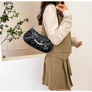 Détail du sac noir à texture crocodile avec chaîne décorative en perles et cœurs