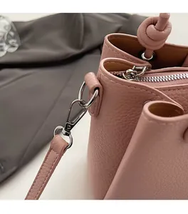Close-up of pink litchi grain leather bucket bag with silver hardware and knotted strap