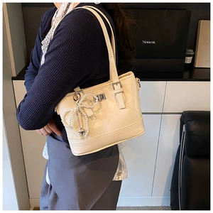 Detail of cream quilted crossbody bag with heart pearl charm and silver lock closure