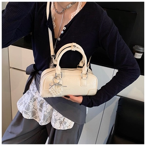 Détail du sac Boston crème avec pendentif cœur en perles et texture de cuir